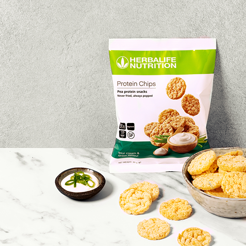 Herbalife skābā krējuma un sīpola proteīna čipsi bļodā ar mērci – veselīga, bezglutēna un olbaltumvielām bagāta uzkoda.