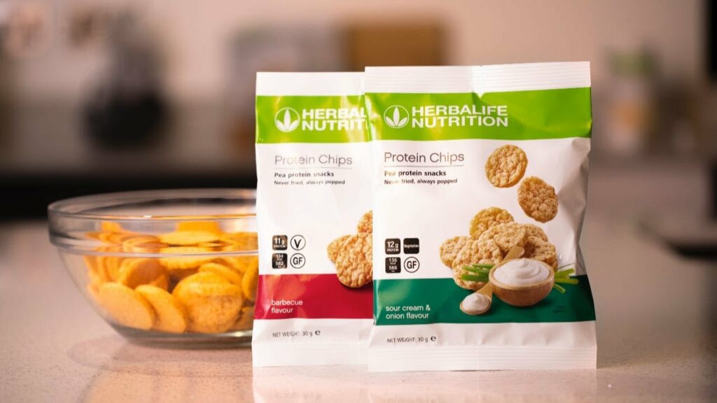 Veselīgas uzkodas – proteīna čipsi ar svaigām mērcēm un dārzeņu salsu uz koka paplātes.