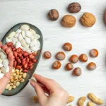 Rieksti un sēklas, kas satur fitātus – redzamas rokas, mizojot ķirbju sēklas