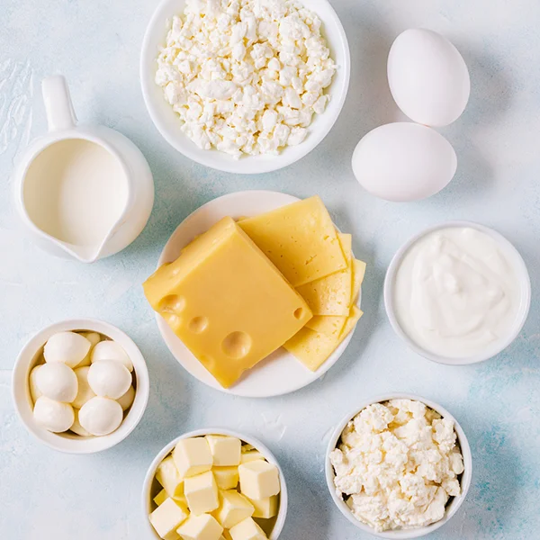 Dažādi piena produkti un olas uz gaiša fona – siers, biezpiens, piens, jogurts, sviests un olas
